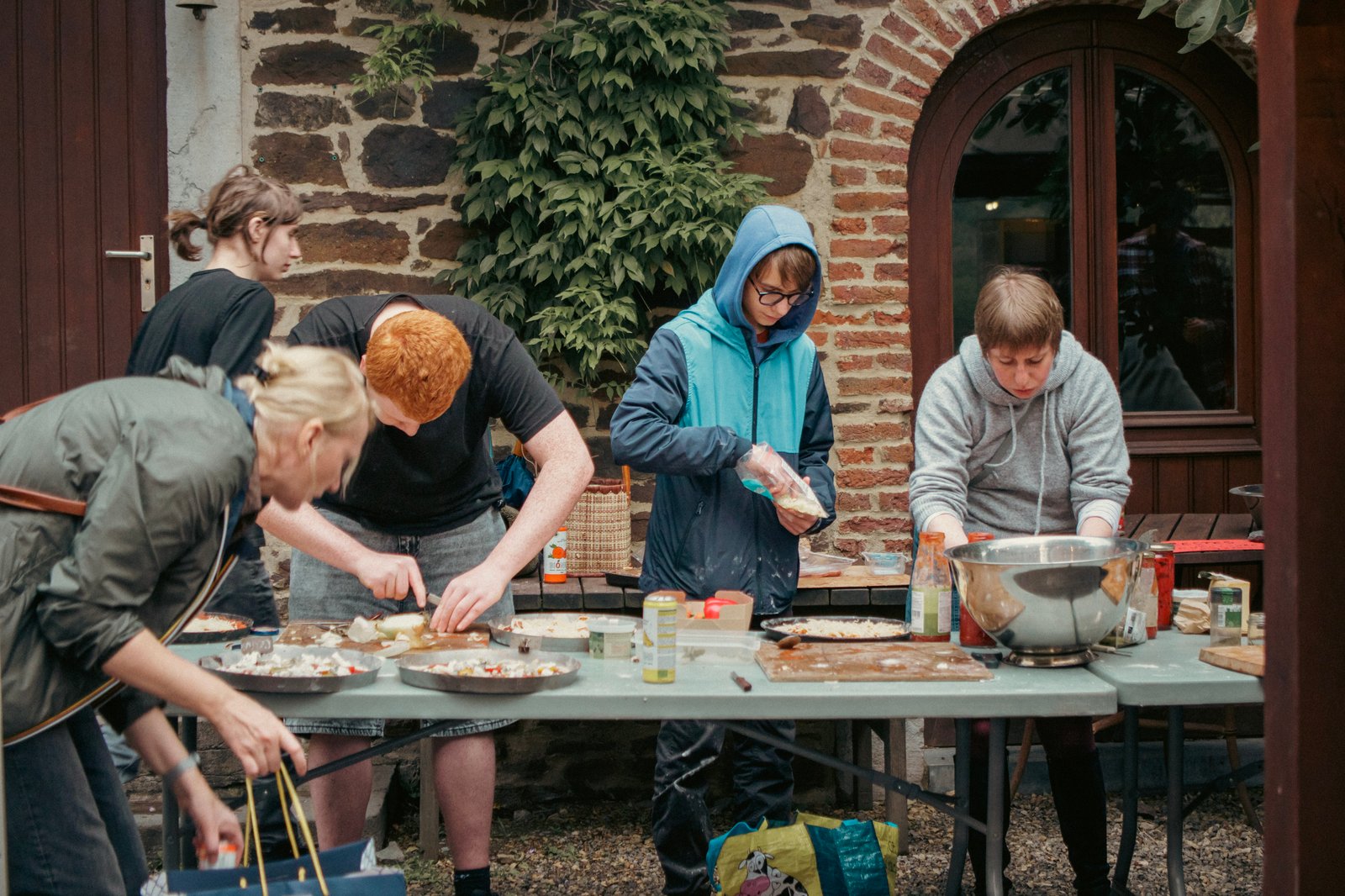 Le groupe garnit ses pizzas dans la cour